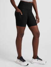 model wearing black 7" inseam biker shorts with pockets on a plain background.